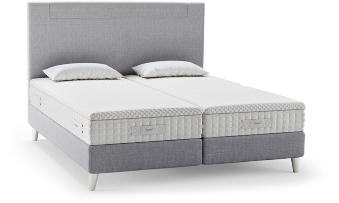 Ein modernes Svane-Bett mit zwei Matratzen und Kissen, das Komfort und Stil für erholsamen Schlaf bietet.