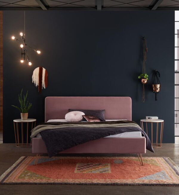 Fliederfarbenes Polsterbett mit Metallfüßen und passenden Nachttischen von Hasena in dunklem Setting