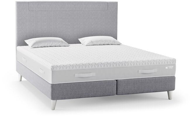 Ein modernes Svane-Doppelbett mit grauem Kopfteil und zwei Kissen auf der Matratze bietet Komfort und Stil im Schlafzimmer.