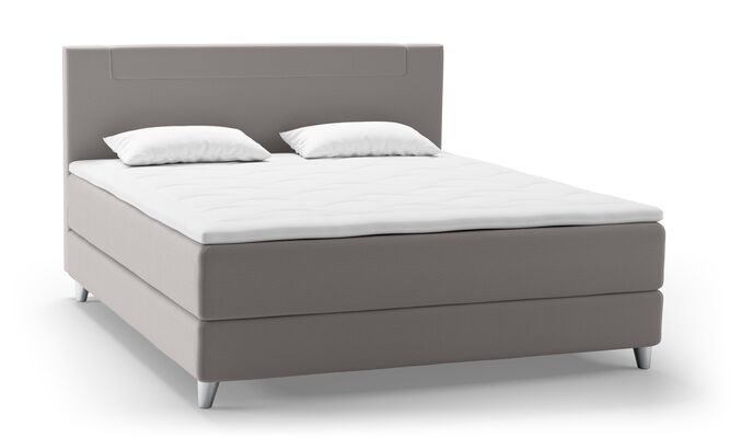 Ein elegantes, graues Boxspringbett mit zwei Kopfkissen und einer weißen Matratze von Svane