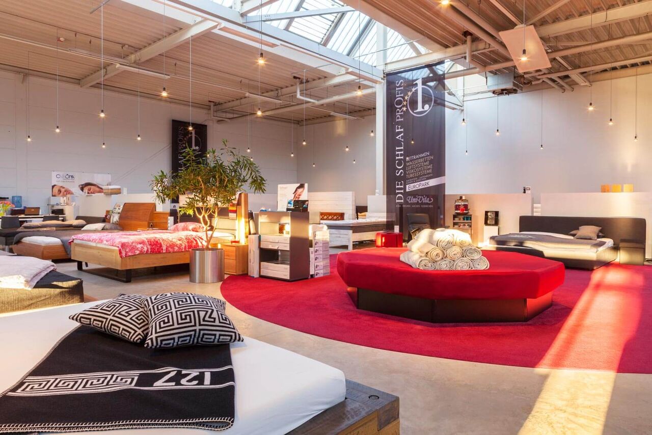 Eine stilvolle Schlafzimmereinrichtung zeigt verschiedene Betten und gemütliche Accessoires in einem modernen Showroom.
