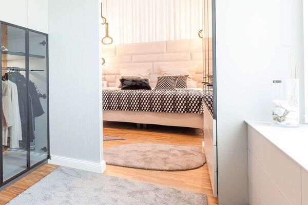 Stimmungsvolles Bild mit Blick auf ein helles Stoffbett mit karierter Bettwäsche