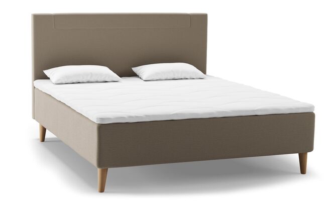 Ein modernes, beiges Bett mit zwei Kopfkissen und einem weißen Bezug steht vor neutralem Hintergrund.