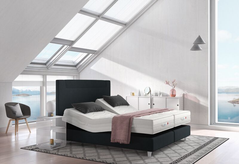 Dumkles Svane-Zleep-Bett mit verstellbaren Lattenrosten und unbezogenen Matratzen in einem hellen Raum mit großen Fenstern