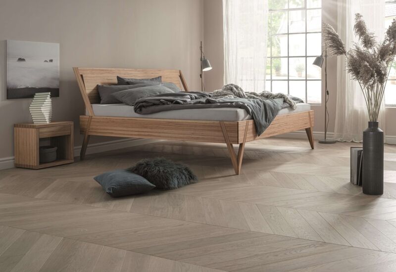 Dormiente Holzbett aus Designbuche in einem Raum mit Holzboden vor einem Fenster
