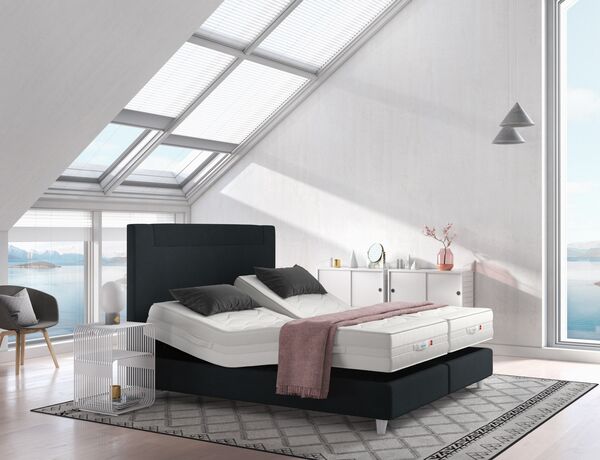 Dumkles Svane-Zleep-Bett mit verstellbaren Lattenrosten und unbezogenen Matratzen in einem hellen Raum mit großen Fenstern