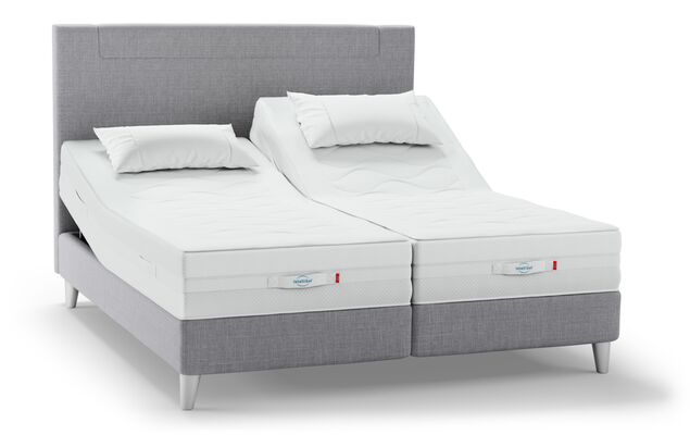 Ein modernes, verstellbares Svane-Doppelbett in nordischem Grau mit zwei Matratzen und Kissen sorgt für individuellen Schlafkomfort.