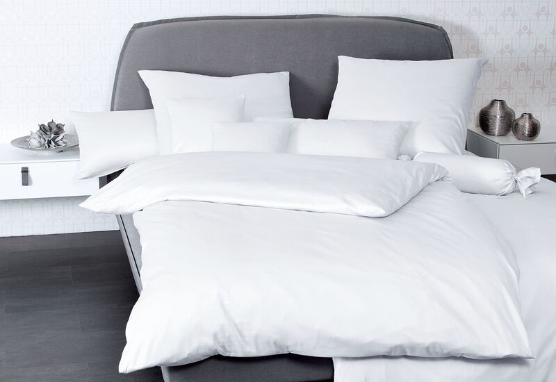 Ein schlichtes graues Bett mit weißer Bettwäsche