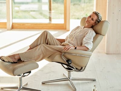 Entspannte Frau in einem beigen Stressless-Sessel mit Fußhocker