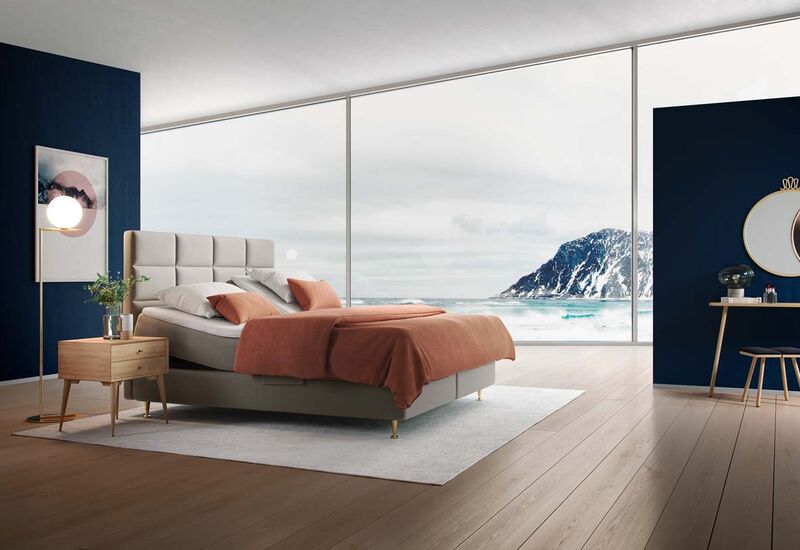 Ein modernes Schlafzimmer mit einem komfortablen Bett, orangefarbener Bettwäsche und Blick auf eine felsige Küstenlandschaft.