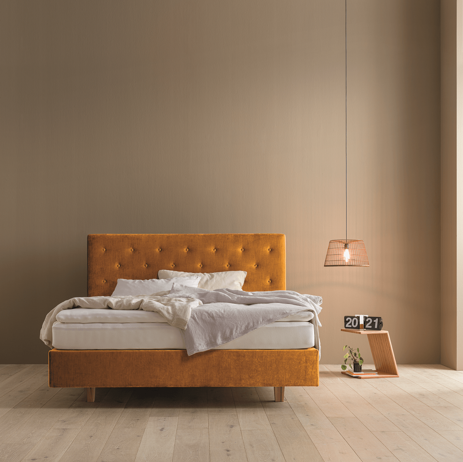 Dormiente Stoffbett in gold/senfgelb in einem beigen Raum mit minimalistischer Ausstattung