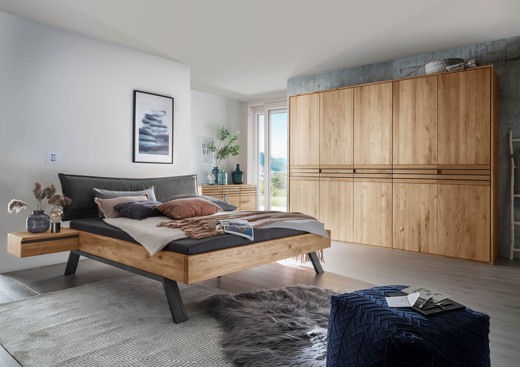 Ein modernes Schlafzimmer mit einem Forestale-Holzbett, eleganter Kommode und großem Kleiderschrank in warmen Holzfarben