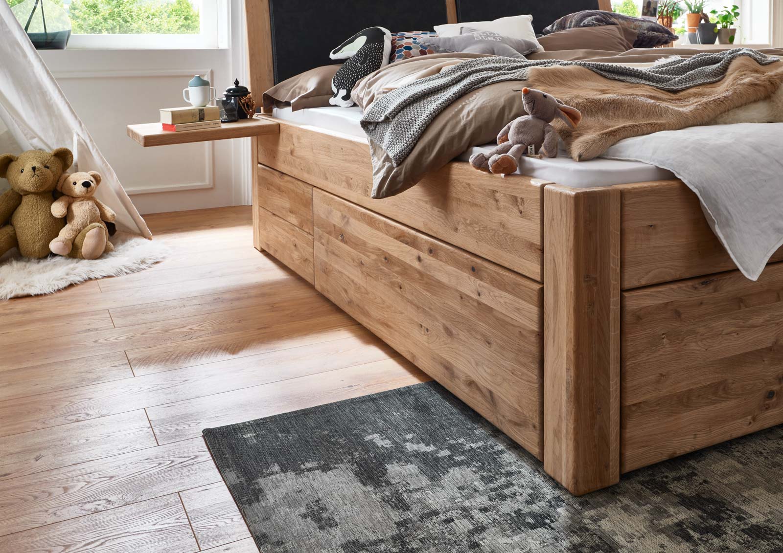 Massivholzbett mit drapierten Kuscheltieren