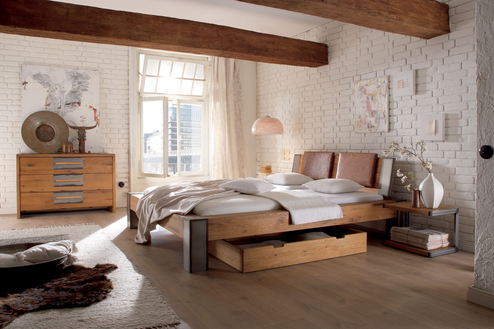Bett der Oak Wild-Serie mit Bettkasten in einem hellen Raum mit weißen Backsteinen und Holzboden
