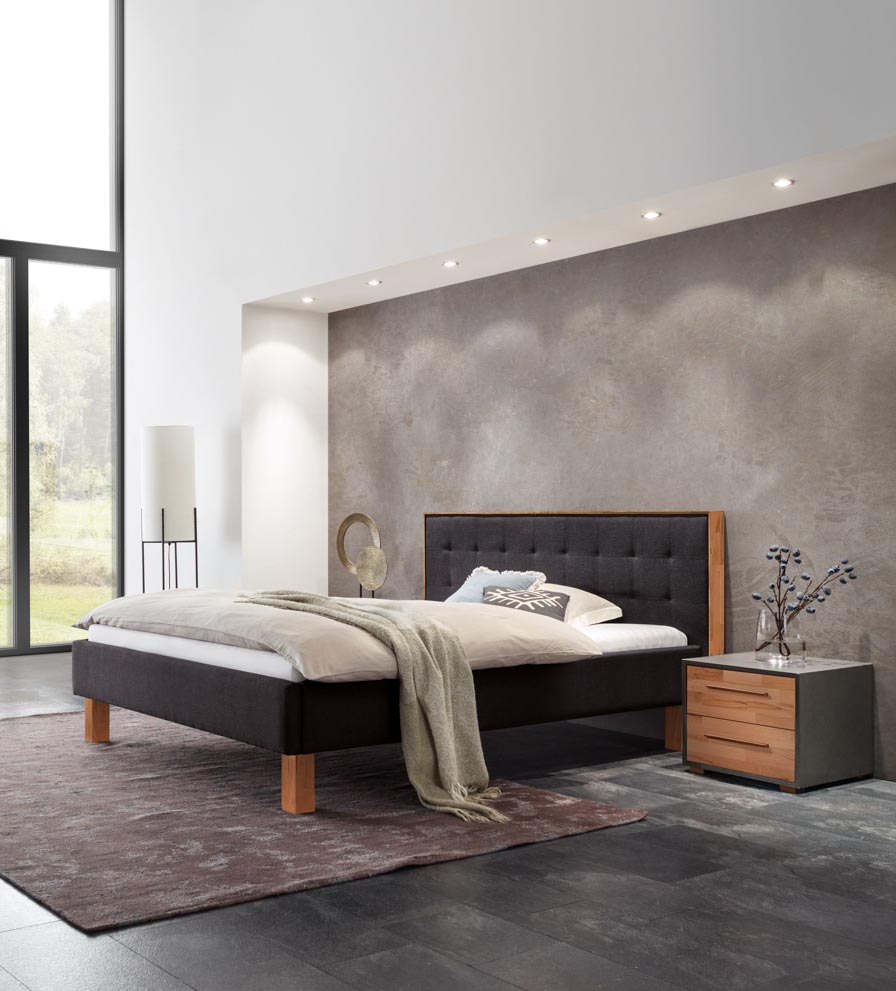 Schwarzes Polsterbett mit Holzfüßen und Nachttisch aus Holt in einem Industrial Style-Zimmer