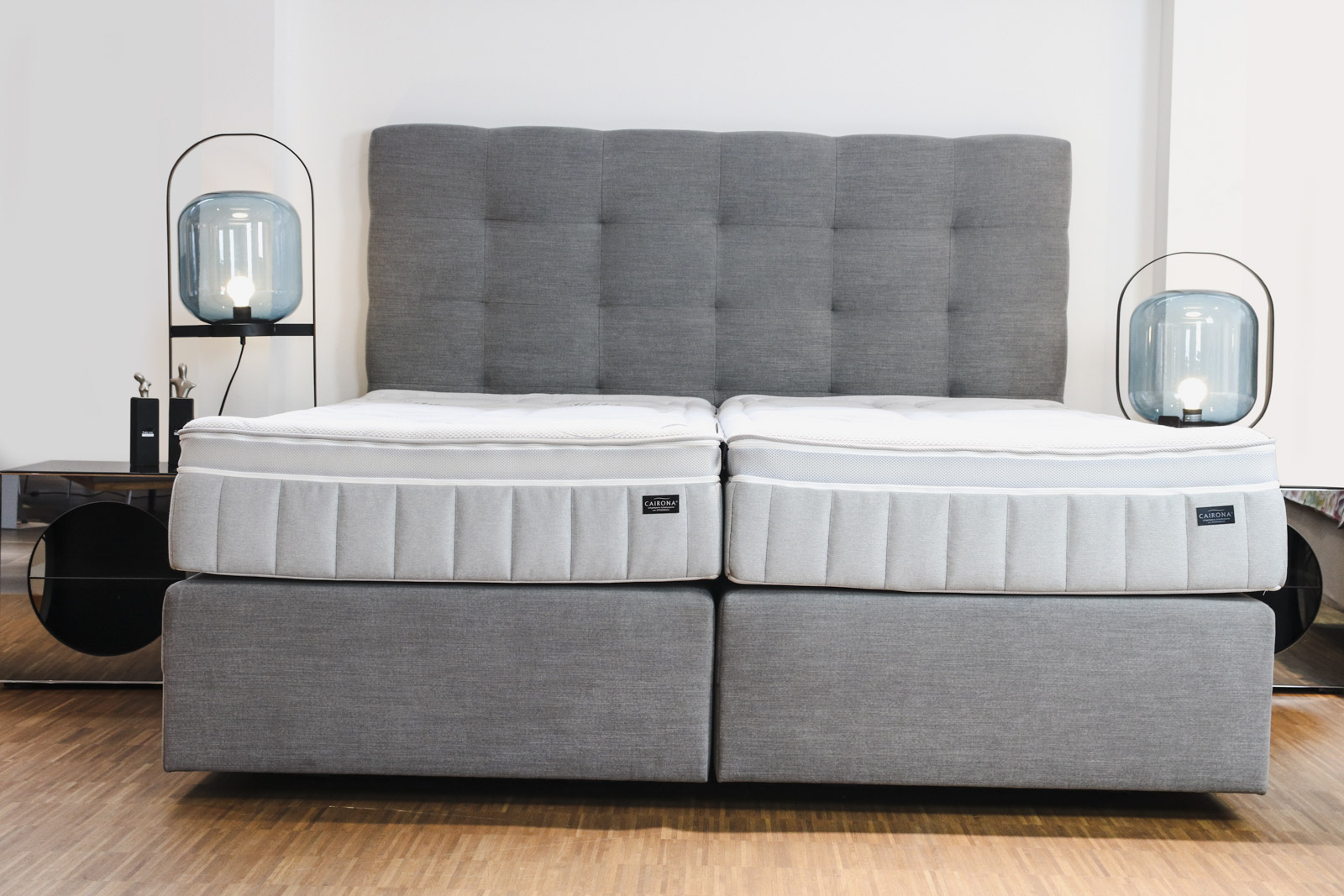 Graues Cairona-Doppelbett mit zwei Einzelmatratzen für mehr Schlafkomfort bei unterschiedlichen Schlafbedürfnissen.