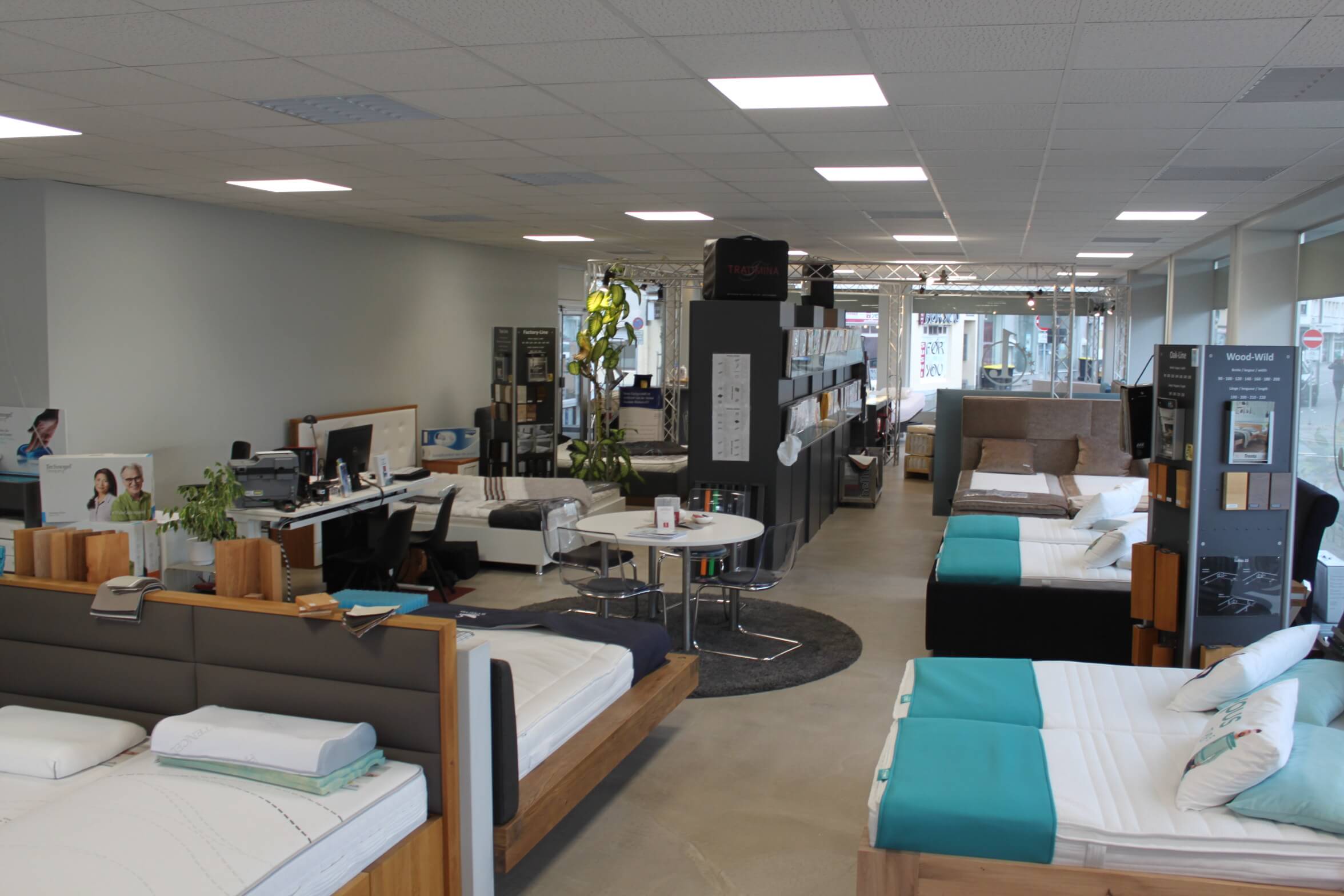 Ein modern gestalteter Möbelgeschäftsraum zeigt verschiedene Betten und Matratzen in einer hellen, offenen Umgebung.