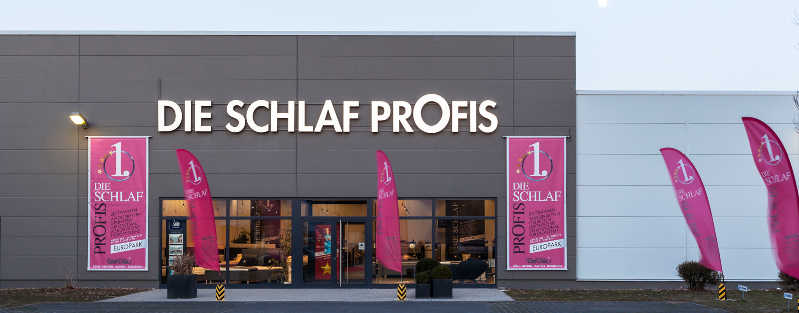 Das Geschäft „Die Schlafprofis“ mit moderner Fassade und auffälligen Bannern und Fahnen in Köln Pulheim.