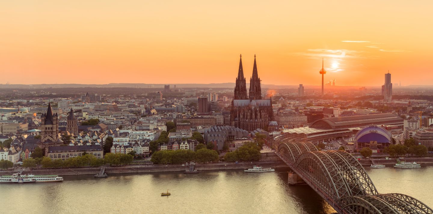 Der Kölner Dom und die Hohenzollernbrücke strahlen im Sonnenuntergang über dem Rhein in Köln.