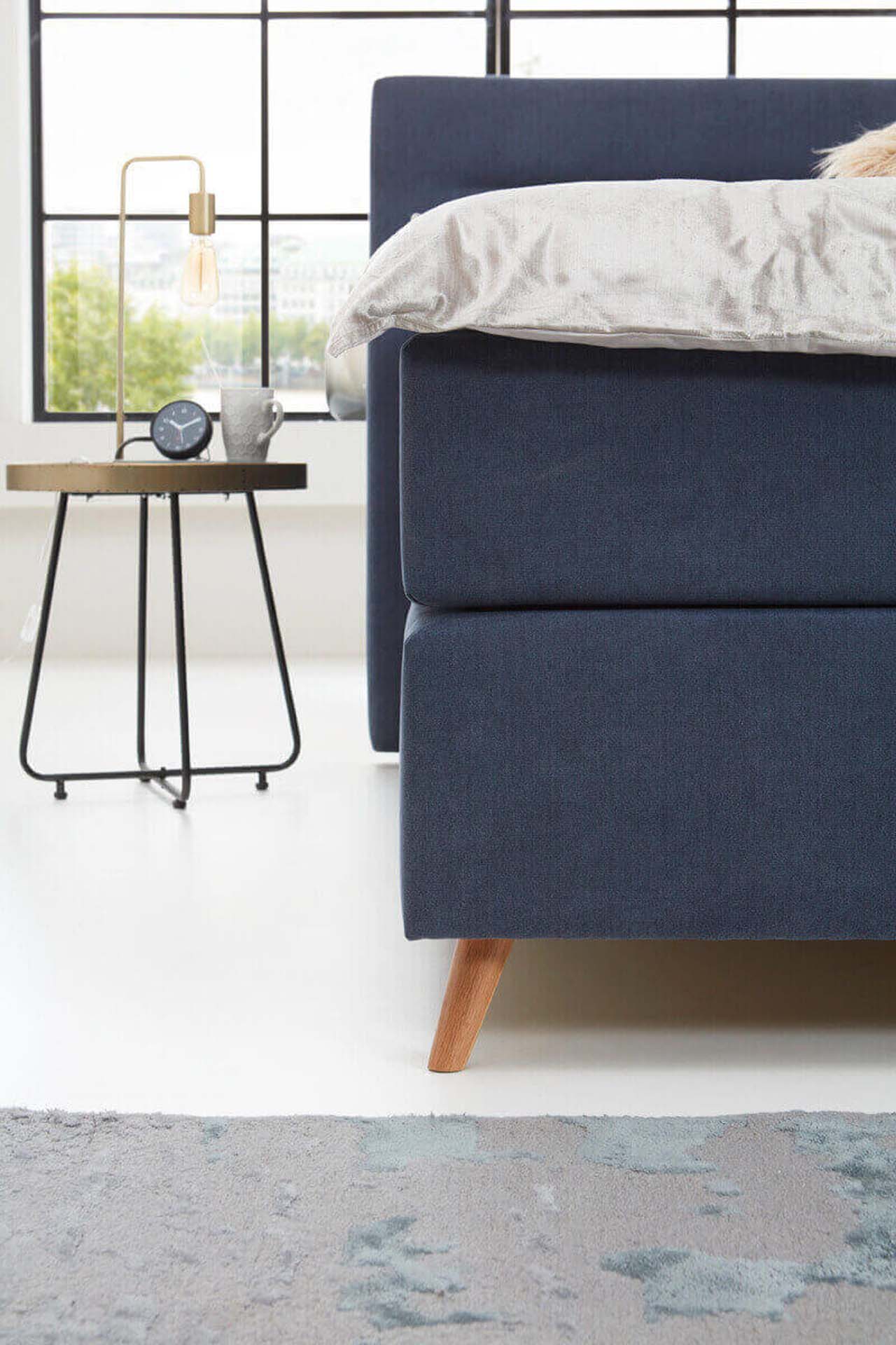 Close-up des Fußteils eines dunkelblauen Polsterbetts.
